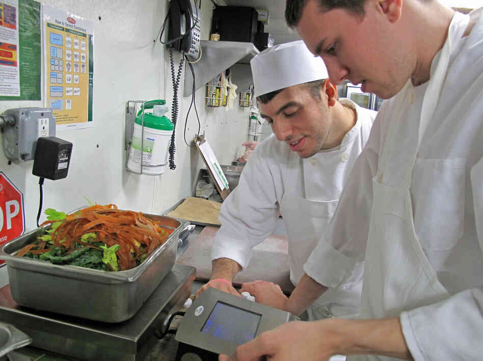 Glen Osterberg (right) and another line cook at Lupa learn how to use the LeanPath waste tracking software.
