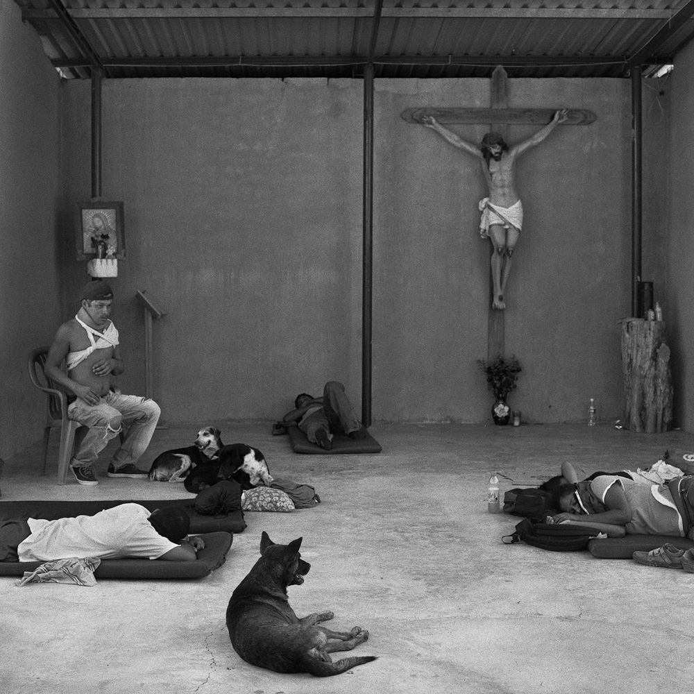 Weary migrants rest in the makeshift chapel of the Hermanos en El Camino migrant shelter in the small town of Ixtepec, in the Mexican state of Oaxaca. June 2009.