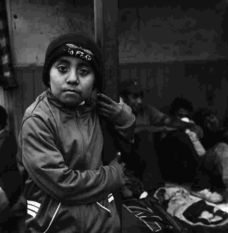 A 9-year-old Guatemalan boy traveling with his mother waits for a train with other migrants seeking shelter from the elements under the tin roof of a concession stand near the tracks in Orizaba. July 2010.