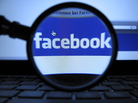 A magnifying glass is posed over a monitor displaying a Facebook page in Munich. A magnifying glass is posed over a monitor displaying a Facebook page in Munich.