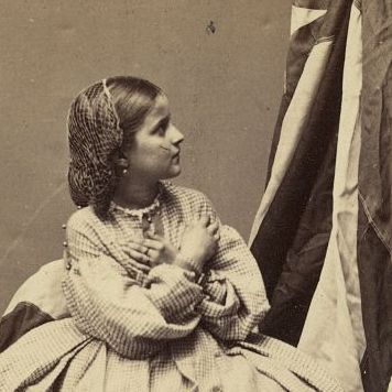 Rebecca Huler, her arms crossed over her chest, while she looks up at the flag.