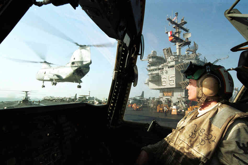 A Navy aviation machinist on the Enterprise watches a Ch-46 Sea Knight fly by after delivering supplies, Oct. 10, 2001. The ship and its carrier battle group were conducting flight operations in Afghanistan following the Sept. 11 attacks.