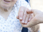 Senior woman in wheelchair holding hands with caretaker Senior woman in wheelchair holding hands with caretaker
