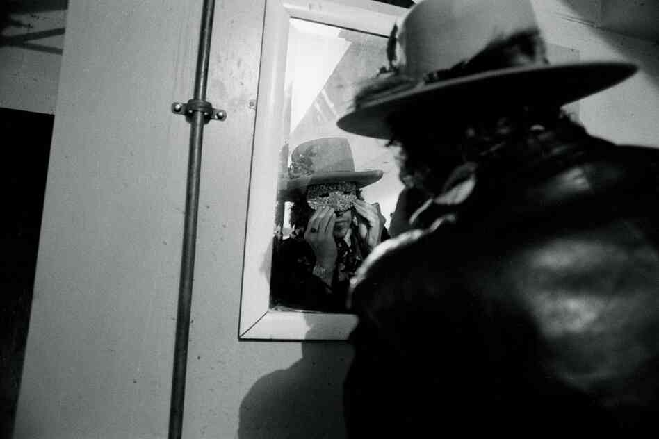 Bob Dylan checking a Halloween mask in the mirror, Plymouth, Mass., Rolling Thunder Revue tour, 1975.