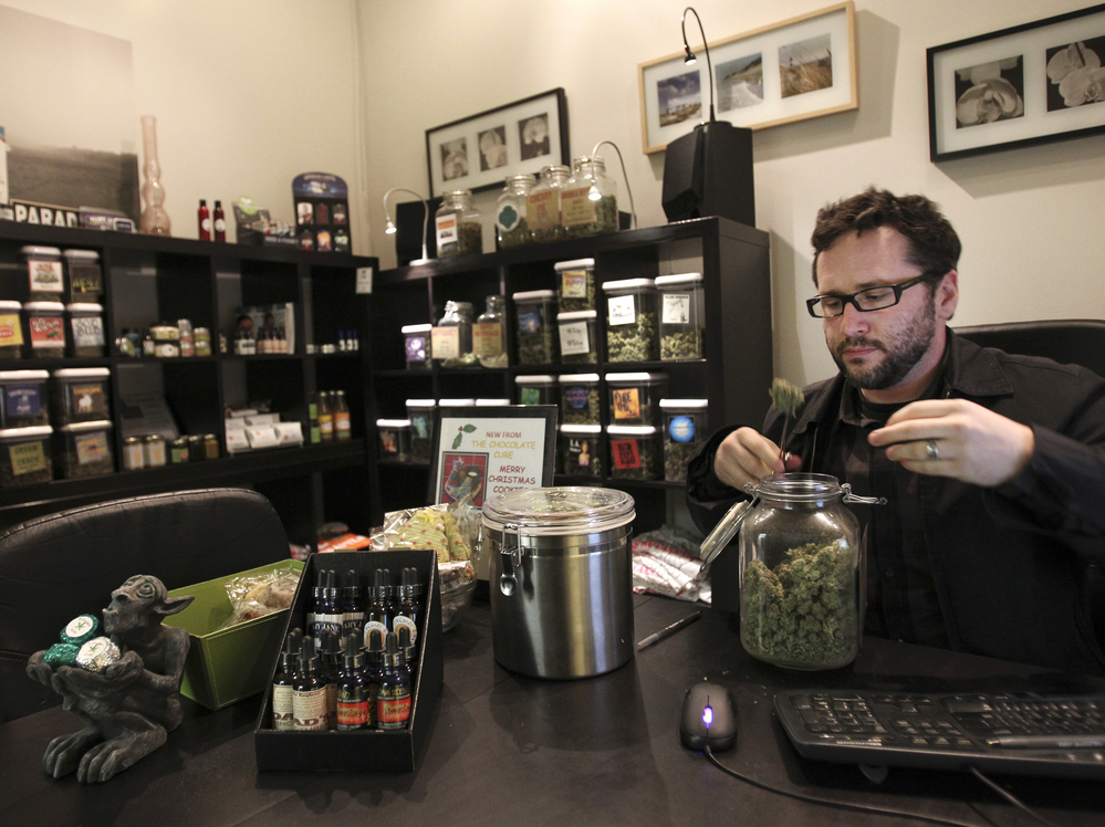 Chris Guthrie, vice president for operations at Canna Pi medical dispensary, inspects a medical marijuana product at his clinic in Seattle on Monday. Marijuana will be legal in Washington state from 12:01 a.m., Thursday.