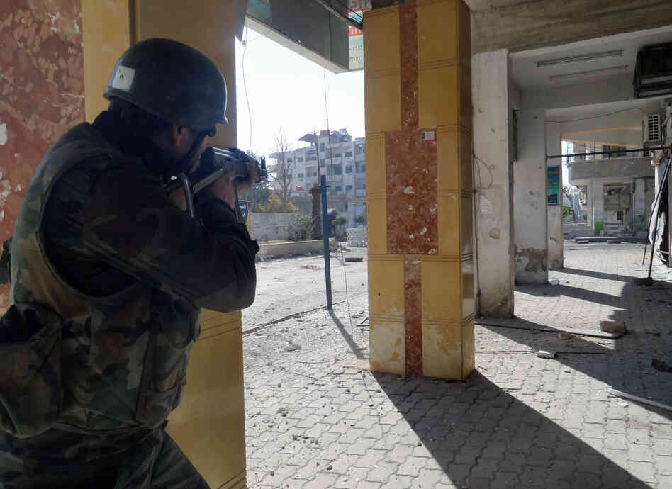 A Syrian soldier aims his rifle during clashes in the Damascus suburb of Daraya on Sunday. There is frequent fighting in and around Damascus, and residents are increasingly worried about a major battle for the capital.