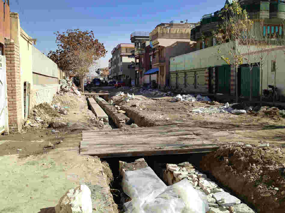 One of the streets undergoing renovation in Kabul. Residents often have to build makeshift bridges at their own expense to span the sewage trenches and reach their garages or driveways.
