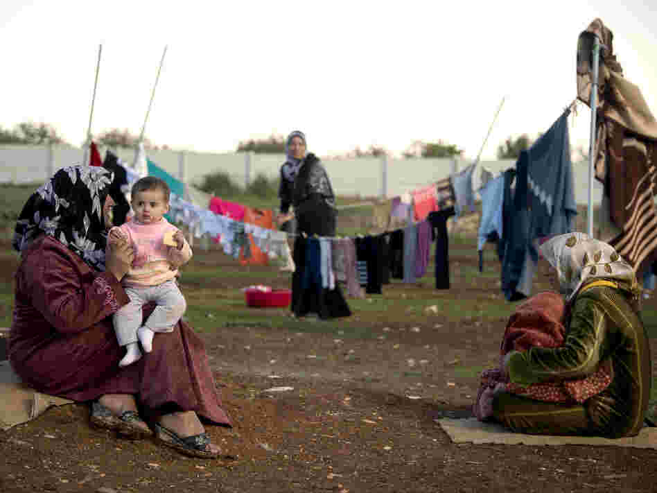 Mothers and their children sit among their washing in a refugee camp on the border between Syria and Turkey near the northern city of Azaz on Wednesday. The internally displaced faced further misery as heavy rain was followed by a drop in temperatures.