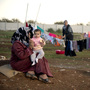 Mothers and their children sit among their washing in a refugee camp on the border between Syria and Turkey near the northern city of Azaz on Wednesday. The internally displaced faced further misery as heavy rain was followed by a drop in temperatures.