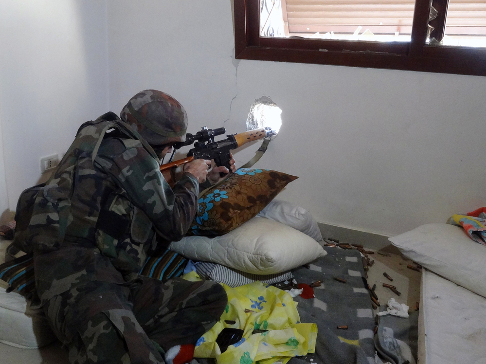 A Syrian soldier aims his rifle during clashes with rebel forces in the Damascus suburb of Daraya on Sunday. The recent fighting around Damascus has raised fears of a looming battle for control of the capital.