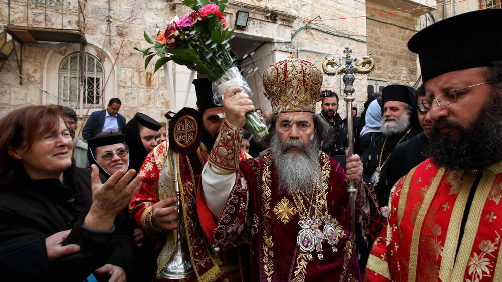 Greek Orthodox Patriarch of Jerusalem Theophilos III, center, splashes holy water toward worshipers after the washing of the feet ceremony in front of the Church of the Holy Sepulcher in Jerusalem on April 16, 2009, during Easter celebrations. A crisis was narrowly averted recently when the church's $2.3 million water bill was waived.