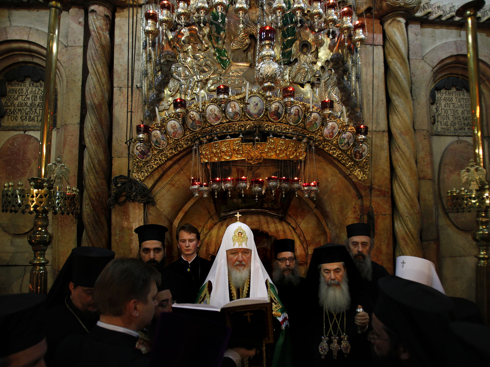 Greek Orthodox Patriarch of Jerusalem Theophilos III (right) and Russian Orthodox Patriarch Kirill (center) pray in front of the tomb of Jesus in the Church of the Holy Sepulcher in November.