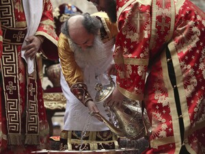Greek Orthodox Patriarch of Jerusalem Theofilos III, center, pours water into a basin during the washing of the feet ceremony outside the Church of the Holy Sepulcher in Jerusalem's Old City on April 21, 2011, during Easter celebrations.