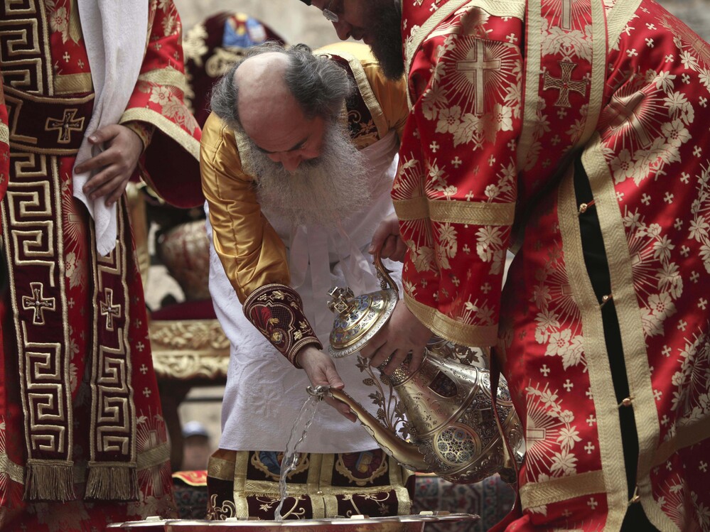 Greek Orthodox Patriarch of Jerusalem Theofilos III, center, pours water into a basin during the washing of the feet ceremony outside the Church of the Holy Sepulcher in Jerusalem's Old City on April 21, 2011, during Easter celebrations.