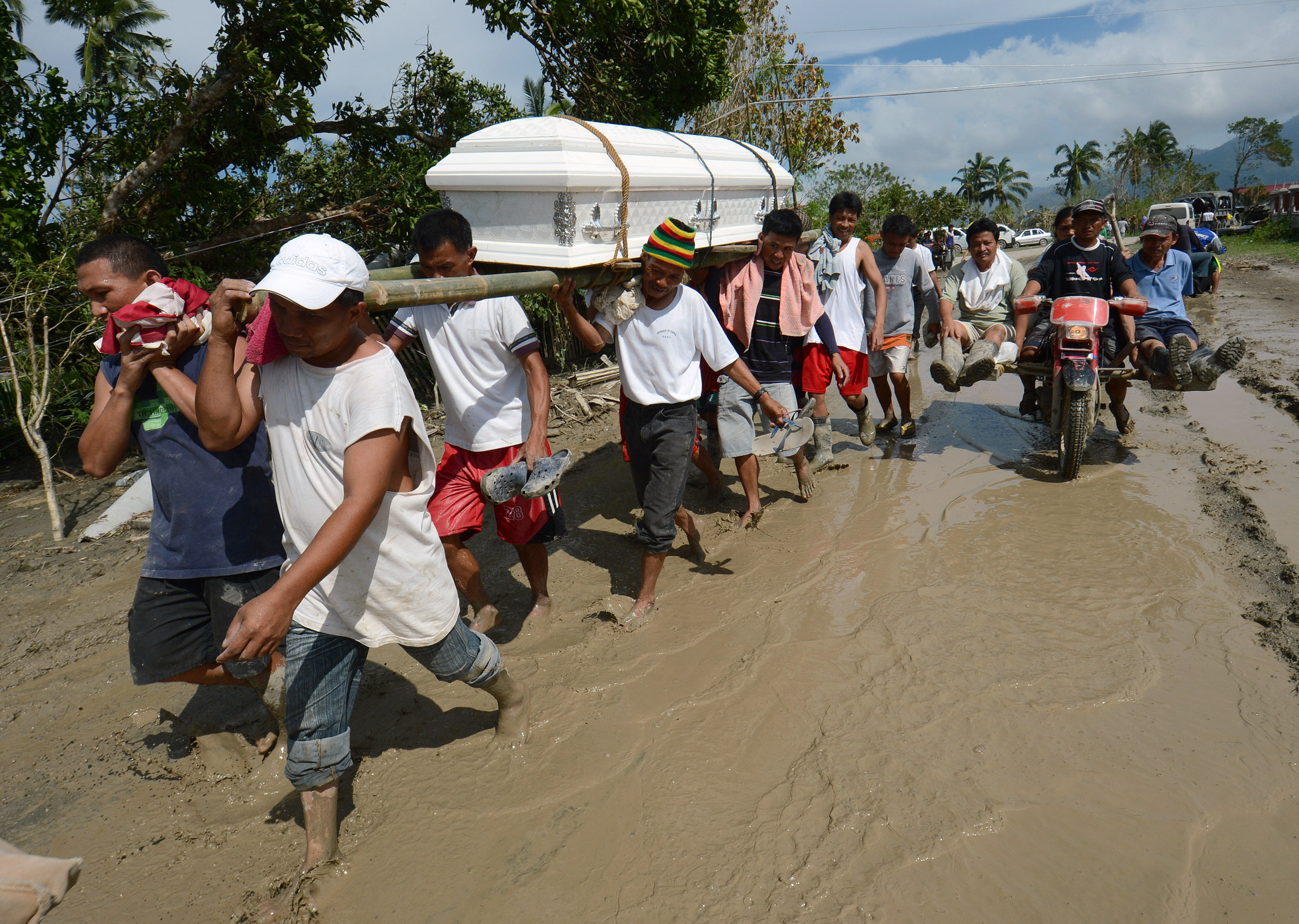 Residents carry a relative's coffin along a muddy road in the town of New Bataan, compostela province on Thursday. Nearly 200,000 people are homeless and more than 300 dead after the Philippines suffered its worst typhoon this year.
