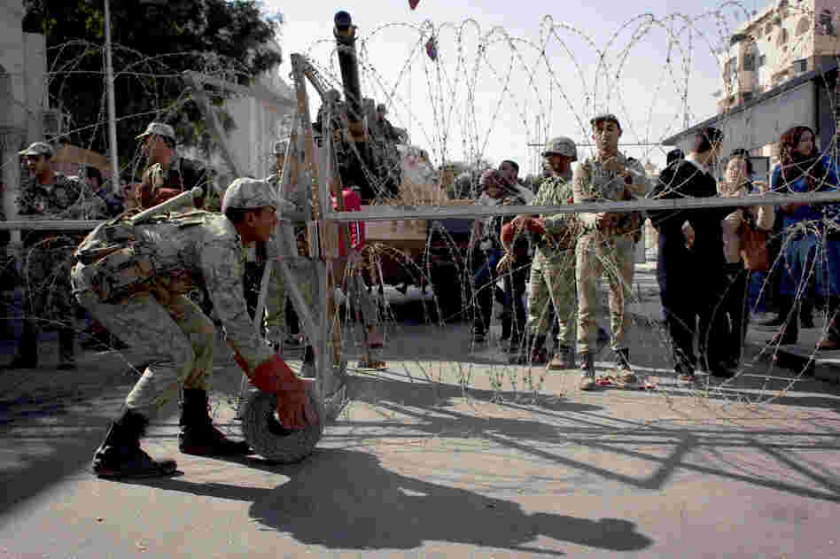 Egyptian army soldiers spread barbed wire near the presidential palace to secure the site after clashes that left several people dead and hundreds wounded.