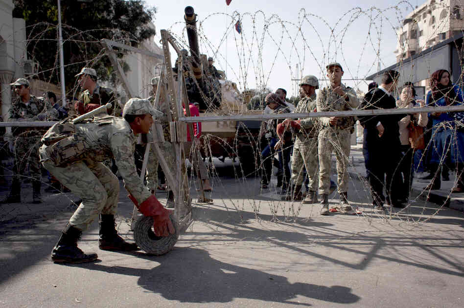 Egyptian army soldiers spread barbed wire near the presidential palace to secure the site after clashes that left several people dead and hundreds wounded.