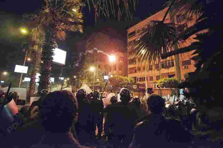Protesters throw a flare at the Egyptian riot police. People on both sides lobbed firebombs and rocks at each other as their standoff over Morsi's expanded powers and an Islamist-drafted constitution turned violent.