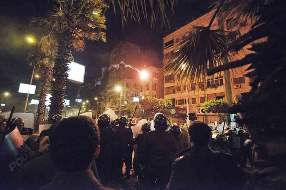 Protesters throw a flare at the Egyptian riot police. People on both sides lobbed firebombs and rocks at each other as their standoff over Morsi's expanded powers and an Islamist-drafted constitution turned violent.