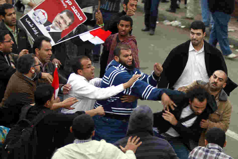 Supporters of the Muslim Brotherhood attack an opposition protester in front of the presidential palace.