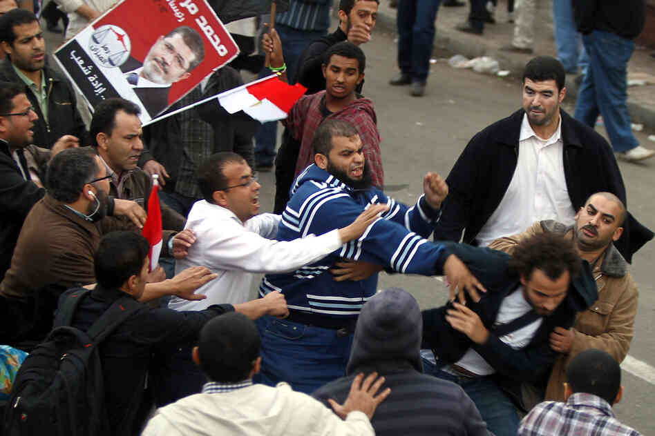 Supporters of the Muslim Brotherhood attack an opposition protester in front of the presidential palace.