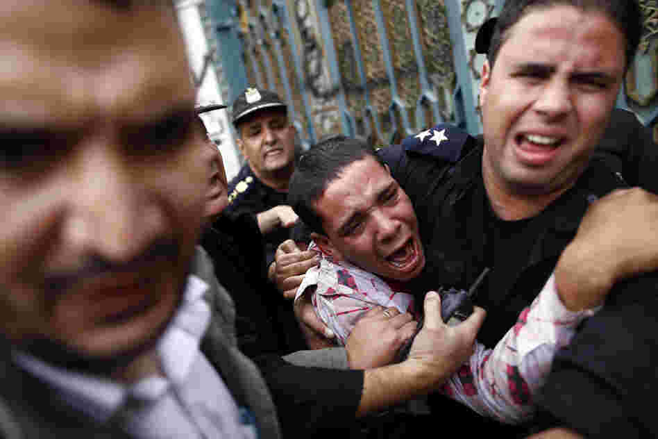 Egyptian policemen protect an opposition demonstrator after a scuffle with members of the Muslim Brotherhood outside the presidential palace in Cairo.