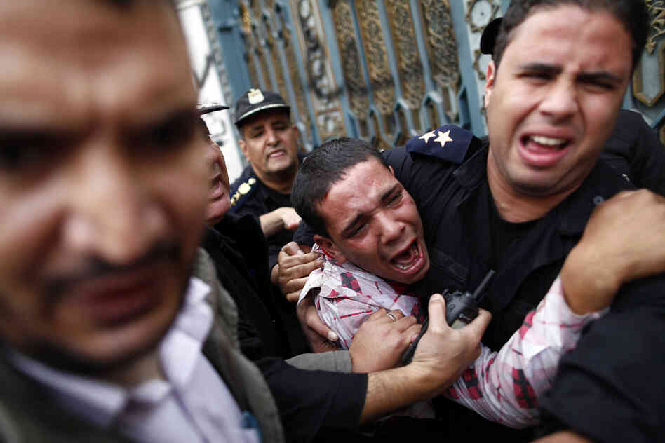 Egyptian policemen protect an opposition demonstrator after a scuffle with members of the Muslim Brotherhood outside the presidential palace in Cairo.
