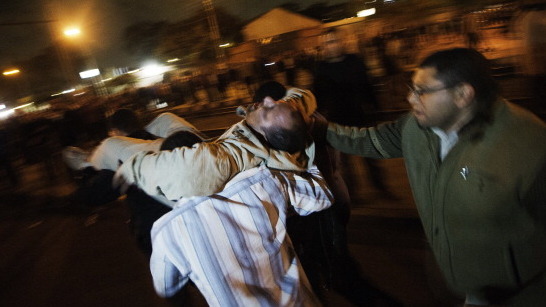 A man who had been with members of the Muslim Brotherhood and supporters of Egyptian President Mohamed Morsi when he was injured during overnight clashes in Cairo is carried from the scene by others.