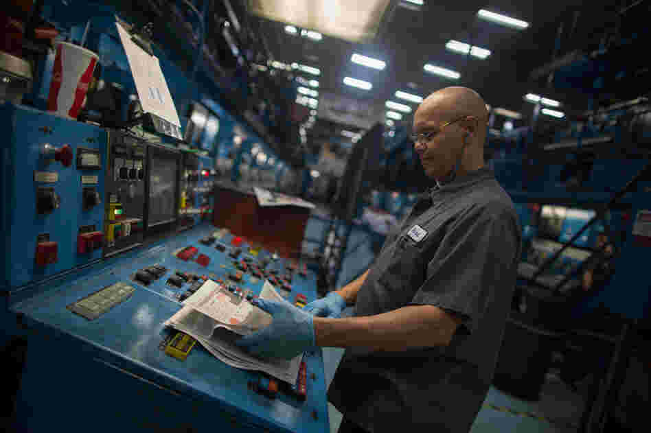 A worker inspects a copy of a paper fresh off the presses at The Orange County Register's facility in Santa Ana.