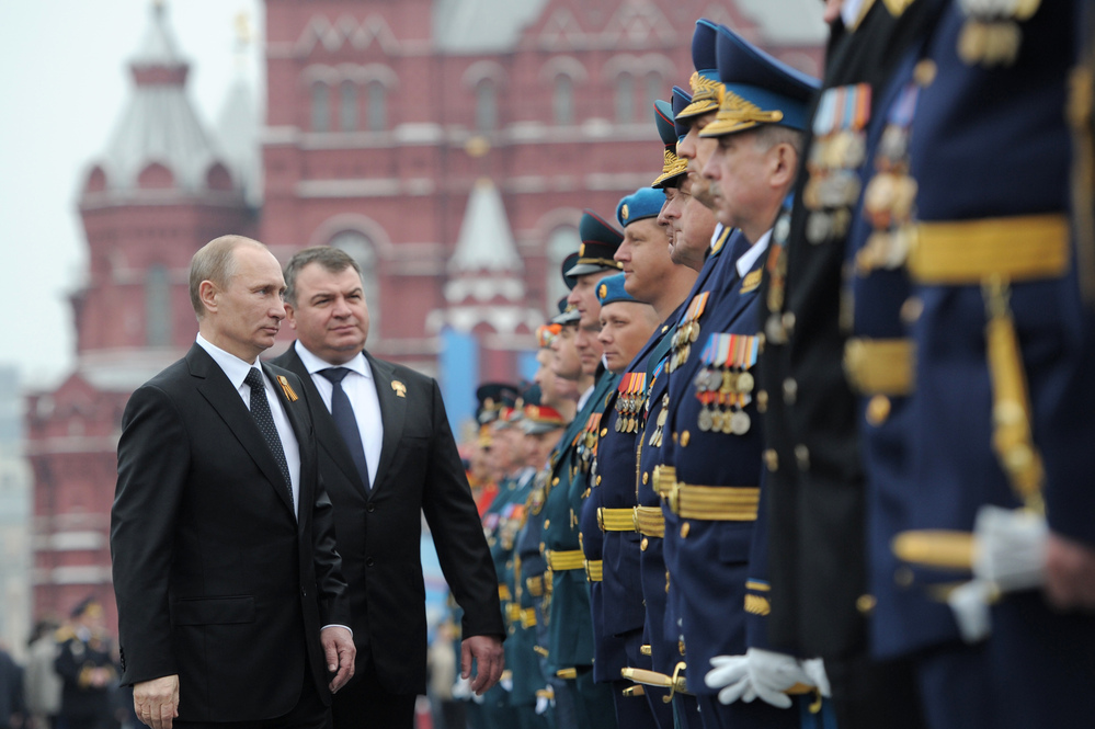 Russian President Vladimir Putin and former Defense Minister Anatoly Serdyukov, who was recently fired, review military officers on Moscow's Red Square in May. Putin's decision to sack Serdyukov has touched off widespread speculation on the motive.