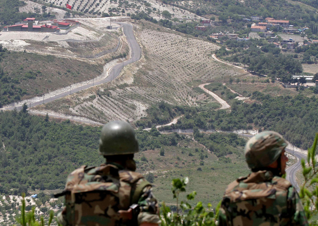In this June 2011 photo, Syrian soldiers look down on the village of Khirbet al-Joz, on the border with Turkey. Syrian rebels recently captured the village, and residents are setting up a secular, democratic leadership they hope will serve as a model.