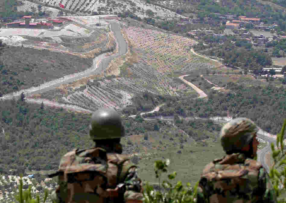 In this June 2011 photo, Syrian soldiers look down on the village of Khirbet al-Joz, on the border with Turkey. Syrian rebels recently captured the village, and residents are setting up a secular, democratic leadership they hope will serve as a model.