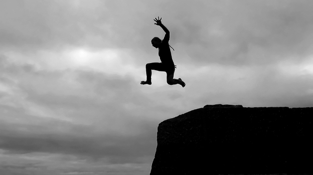 A boy jumps into the sea from high above in the harbor of Mousehole, Cornwall, England.