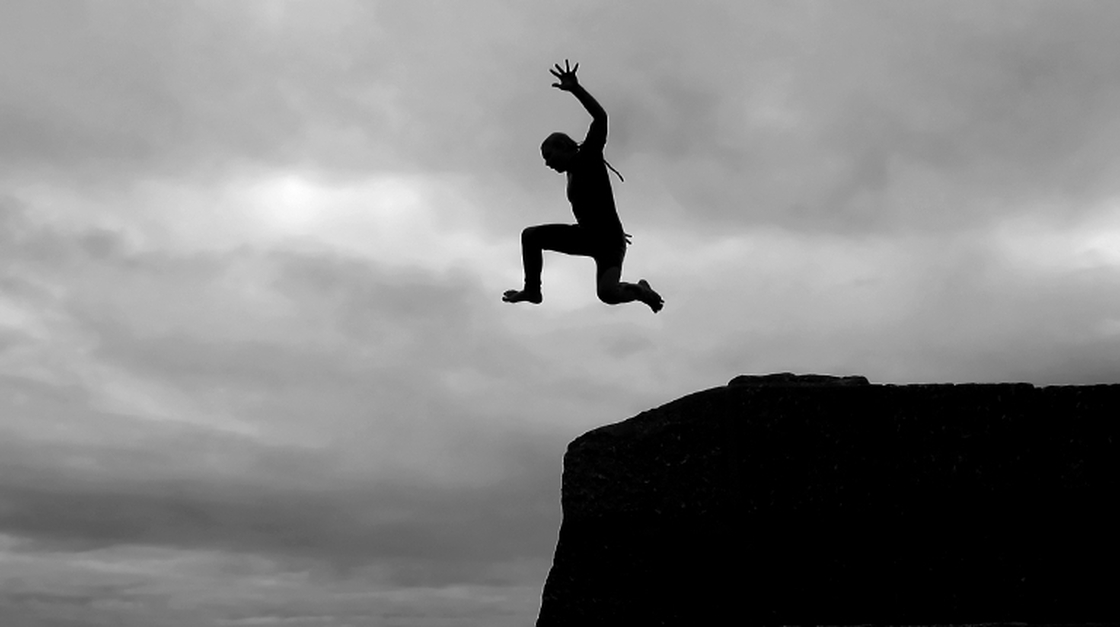 A boy jumps into the sea from high above in the harbor of Mousehole, Cornwall, England.