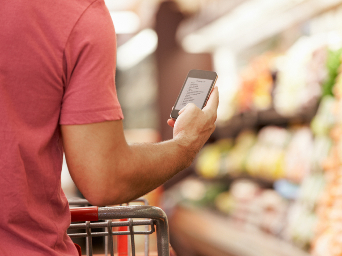 Close Up Of Man Reading Shopping List From Mobile Phone In Supermarket