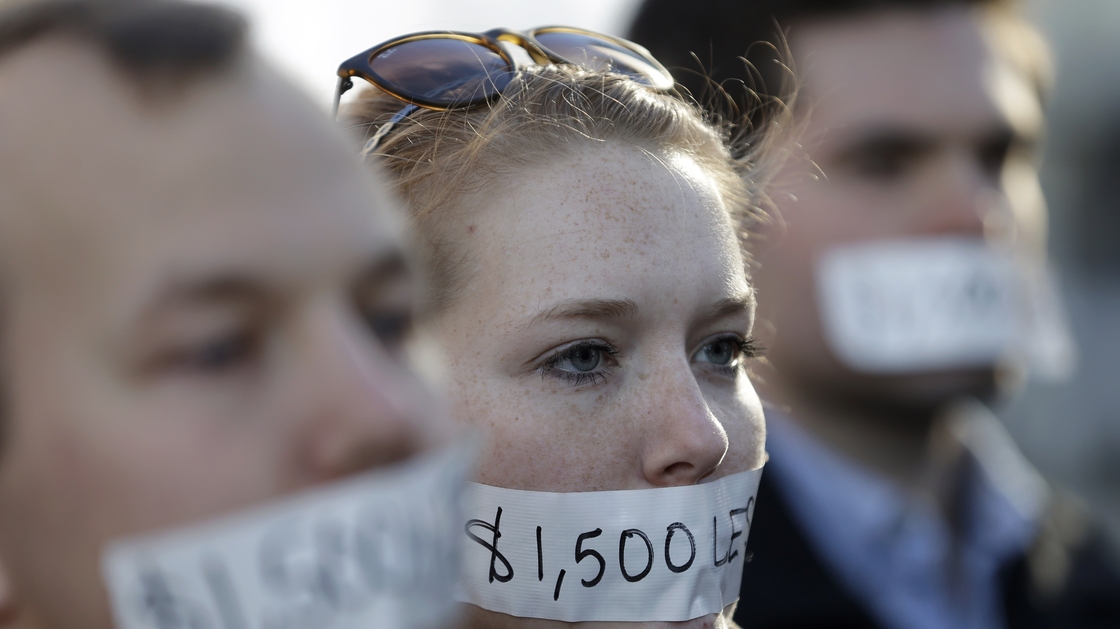 Silent protesters Wednesday in Lansing, Mich., wear tape with messages that signify wages they say they could lose because of the state's new right-to-work law.
