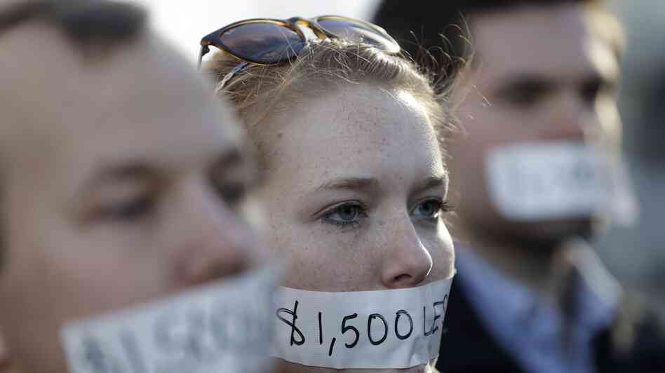 Silent protesters Wednesday in Lansing, Mich., wear tape with messages that signify wages they say they could lose because of the state's new right-to-work law.