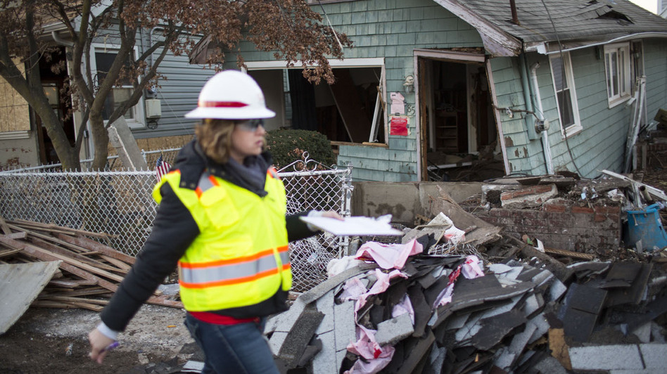 A woman with the Army Corps of Engineers documents a destroyed home last month in a residential area of New Dorp Beach on Staten Island in New York City.