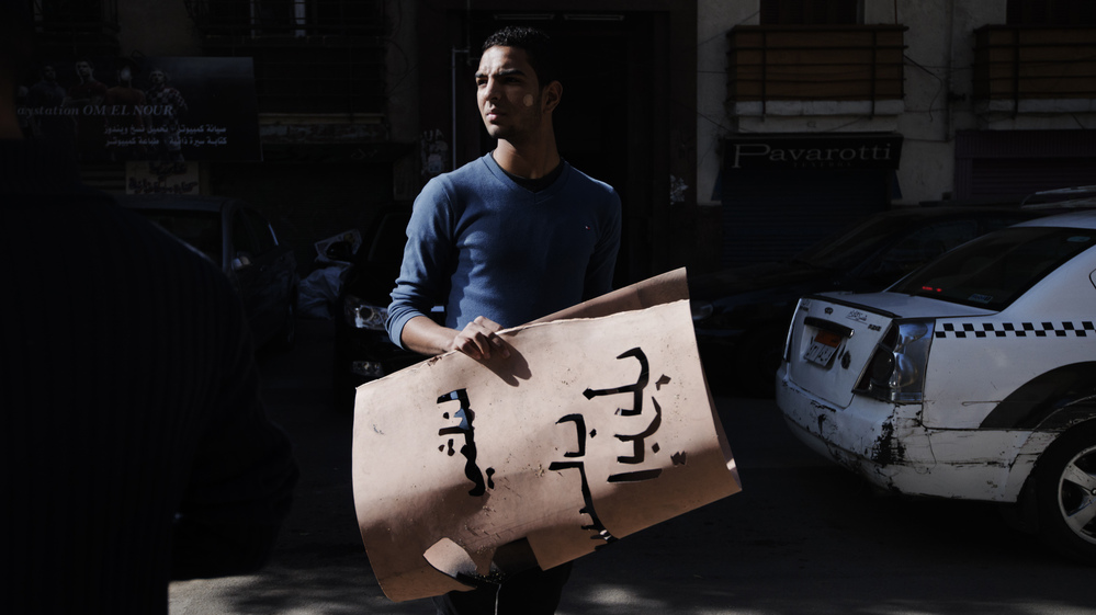 An Egyptian activist holds a banner used to spray-paint graffiti on a wall urging Egyptians to vote against a draft constitution. The opposition says the constitution does not represent all Egyptians, but its efforts have not been particularly well-organized. President Mohammed Morsi and his Islamist supporters support the draft constitution. Voting begins Saturday.