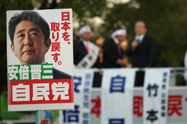 Supporters hold up posters of Japan's former Prime Minister Shinzo Abe at a rally in Osaka on Thursday. Considered a nationalist hawk, Abe is expected to become prime minister for a second time after parliamentary elections Sunday.