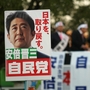 Supporters hold up posters of Japan's former Prime Minister Shinzo Abe at a rally in Osaka on Thursday. Considered a nationalist hawk, Abe is expected to become prime minister for a second time after parliamentary elections Sunday. Supporters hold up posters of Japan's former Prime Minister Shinzo Abe at a rally in Osaka on Thursday. Considered a nationalist hawk, Abe is expected to become prime minister for a second time after parliamentary elections Sunday.
