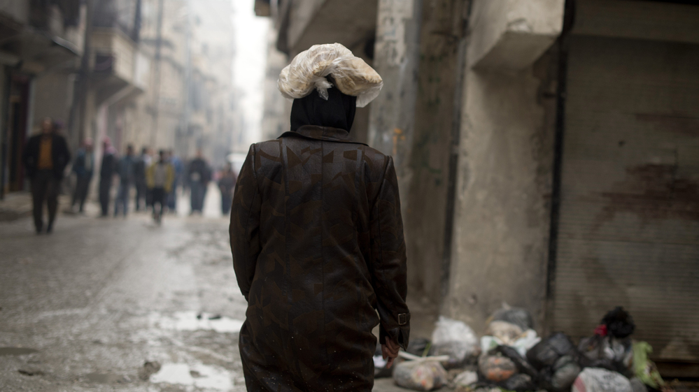 A Syrian woman carries a ration of bread on her head in the northern city of Aleppo. The Syrian opposition now runs local councils in many cities, particularly in the north. They often face major challenges in providing basics likes food, water and electricity.