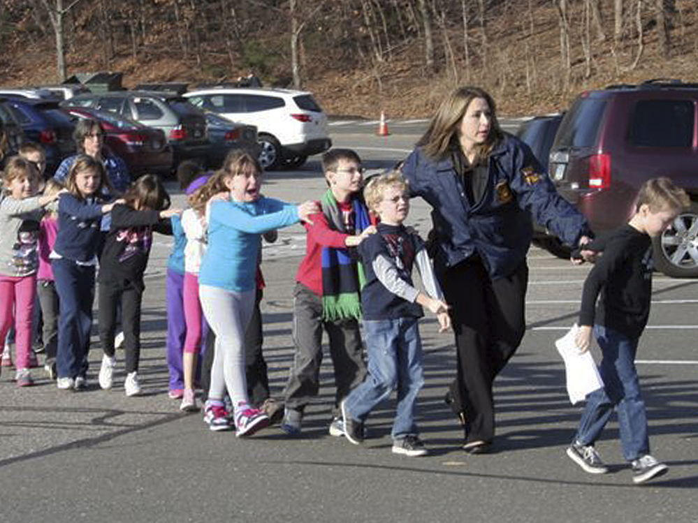 In this photo provided by the Newtown Bee, Connecticut State Police lead children from the Sandy Hook Elementary School in Newtown, Conn., following a shooting there Friday.