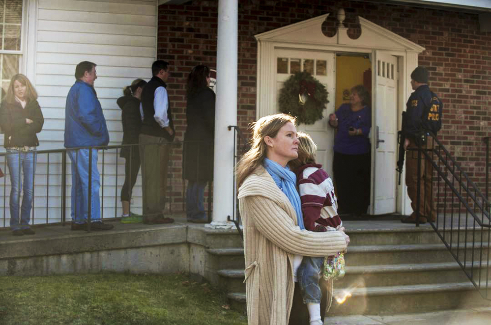 A woman holds a child as people line up to enter the Newtown Methodist Church near the scene of the elementary school shooting in Newtown, Conn.