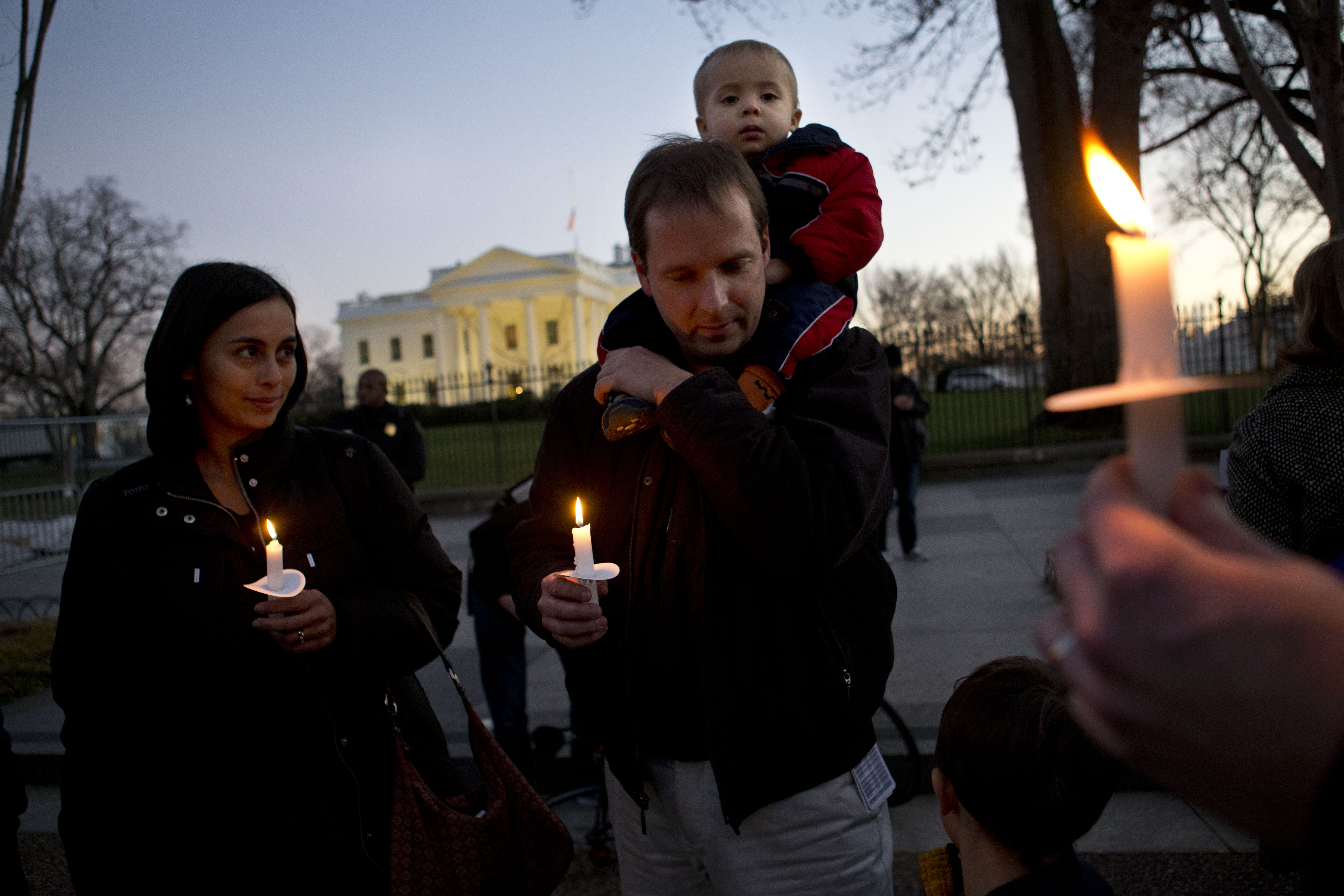 Fabiola Cordova, left, her husband Chris Homan with their son Leo, 2, attend a candlelight vigil in front of the White House on Friday. Fabiola Cordova, left, her husband Chris Homan with their son Leo, 2, attend a candlelight vigil in front of the White House on Friday.