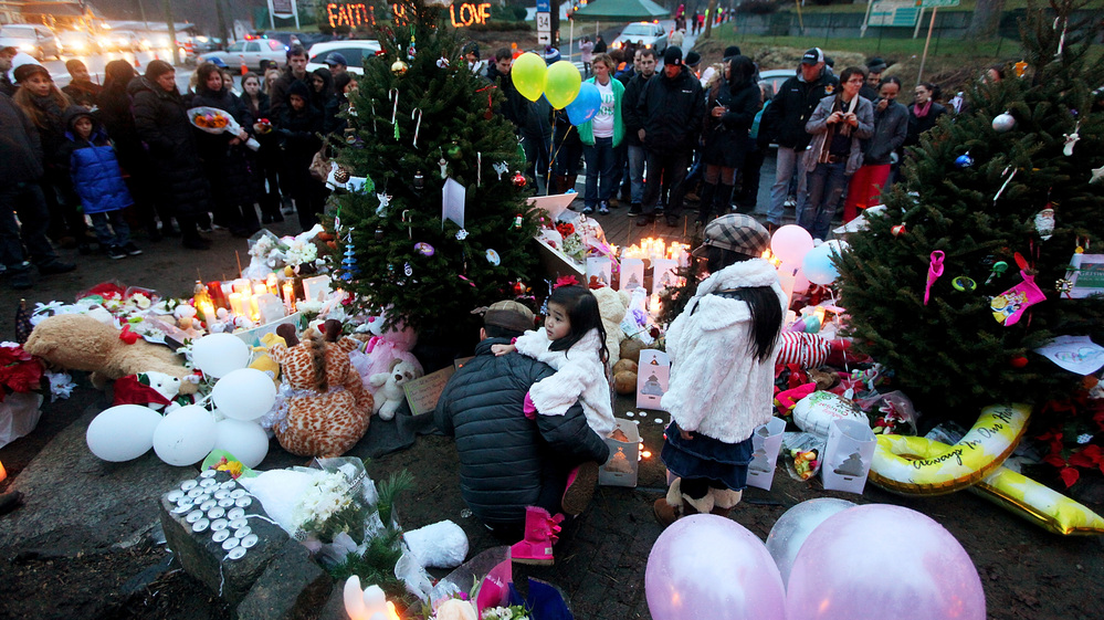 People gather at a memorial for victims near Sandy Hook Elementary School in Newtown, Conn., Sunday. President Obama is visiting the town today to meet with parents and families who lost loved ones in the attack.