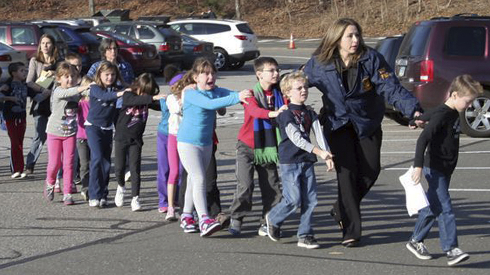 In a photograph taken by Shannon Hicks, police and teachers lead children away from Sandy Hook Elementary. Hicks is a volunteer firefighter, in addition to being an associate editor at the local paper.