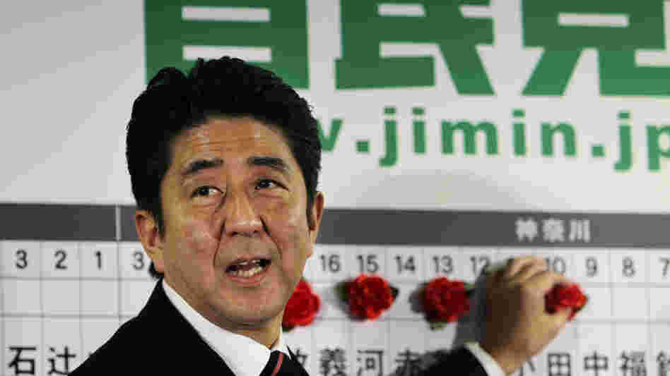 Shinzo Abe of Japan's Liberal Democratic Party marks the name of a parliamentary election winner at party headquarters in Tokyo on Sunday. Japan's conservative LDP stormed back to power Sunday after three years in opposition.