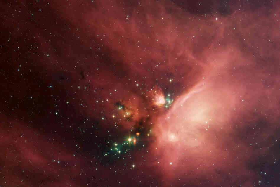 "This image of the Rho Ophiuchi dark cloud ... shows newborn stars peeking out from beneath a dust blanker."
