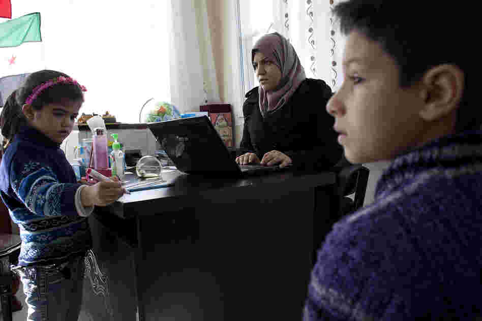 Principal Sally Albunni enrolls  Nureddin, 11, (right) who arrived in Antakya with his mother after his father was killed two weeks earlier in Syria.